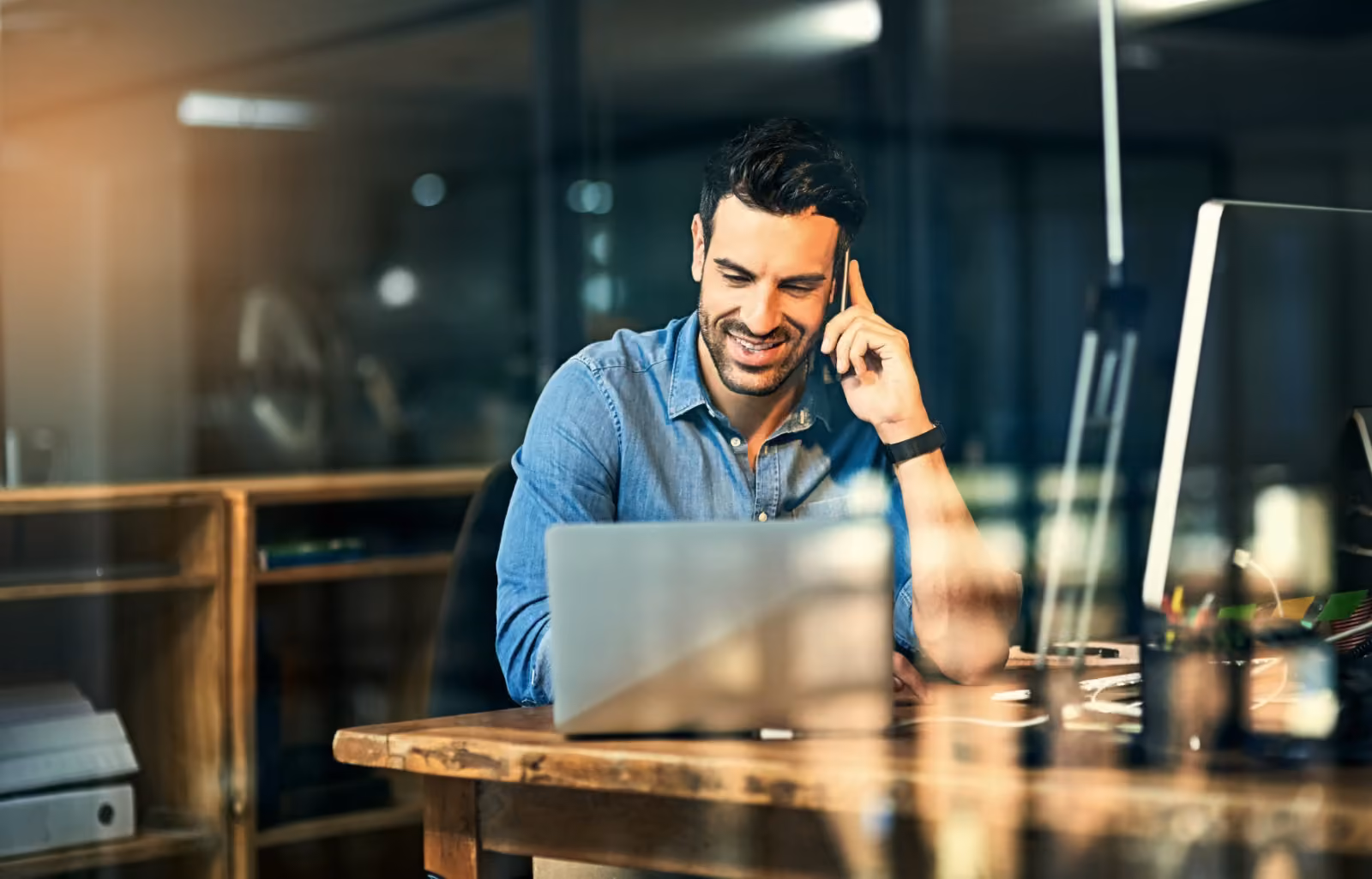 A real estate professional talks on the phone while working on a laptop.